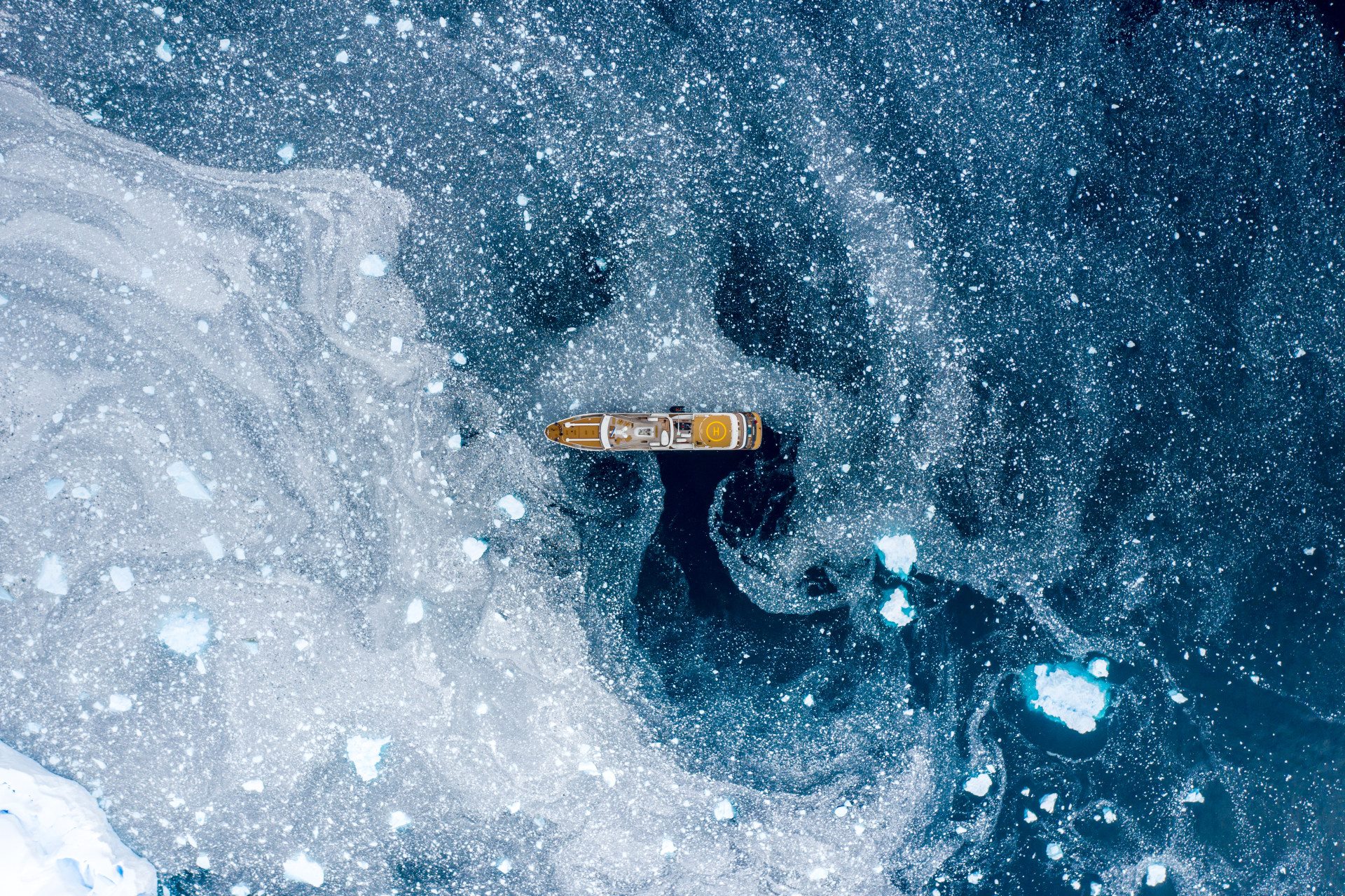 Surrounded by clumps of ice and snow in the Antarctic Peninsula, a yacht appears to be floating adrift in the cosmos.